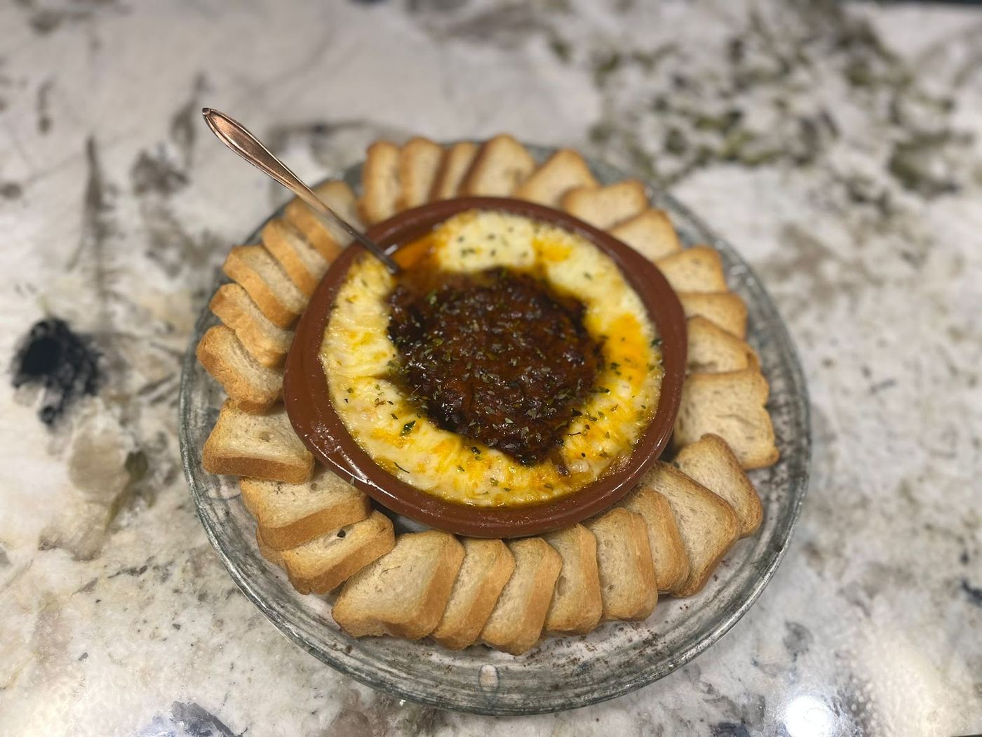 Queso fundido con pisto casero servido con tostas de pan crujiente